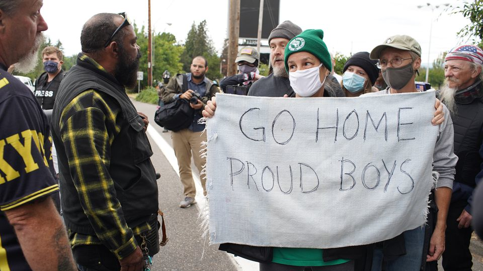 A counter demonstrator holds a sign reading 'Go home Proud Boys' at a right-wing gathering in Northeast Portland on Sunday.