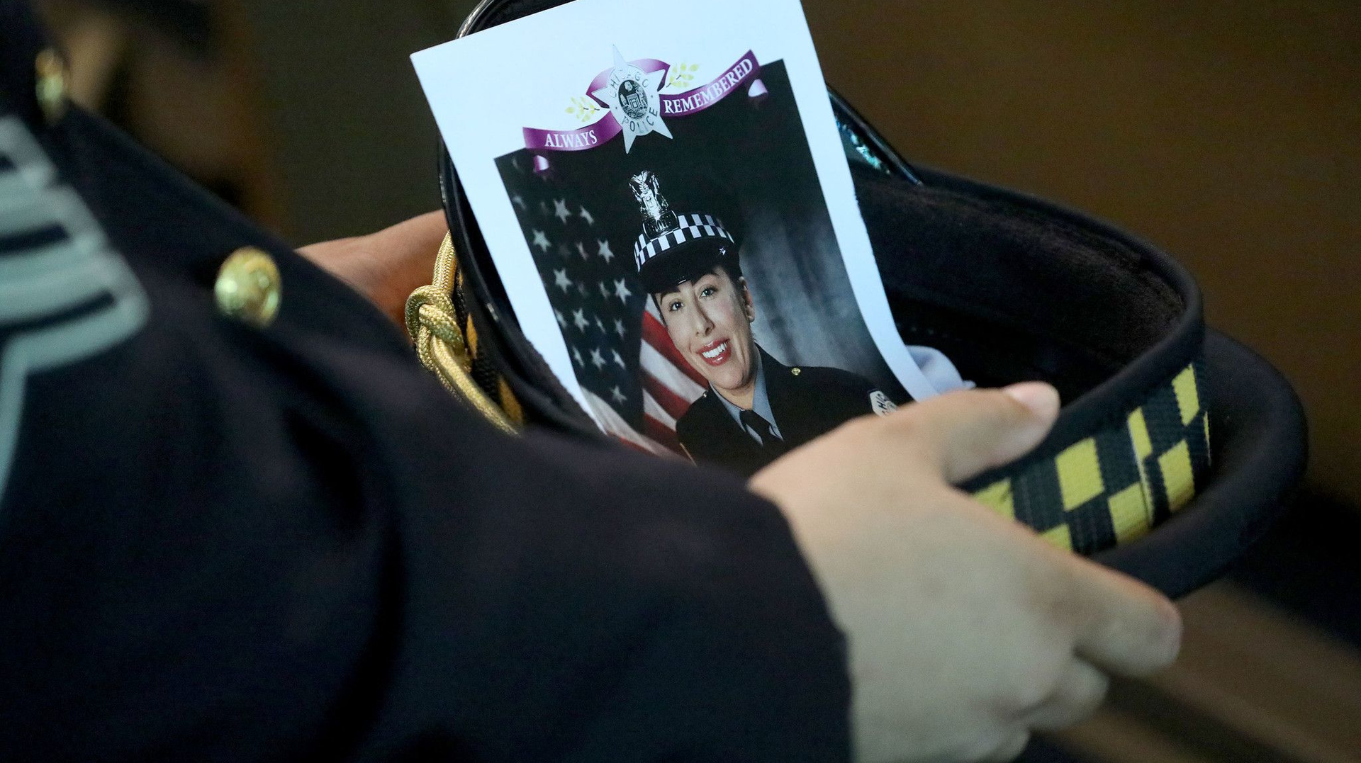 A Chicago police officer holds an image of Officer Ella French in his hat during her funeral service Aug. 19 at St. Rita of Cascia Shrine Chapel.