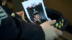 A Chicago police officer holds an image of Officer Ella French in his hat during her funeral service Aug. 19 at St. Rita of Cascia Shrine Chapel.