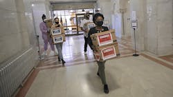 Corenia Smith, campaign manager with Yes 4 Minneapolis, carries boxes of signed petitions calling for replacing the Minneapolis Police Department with a new public safety department.