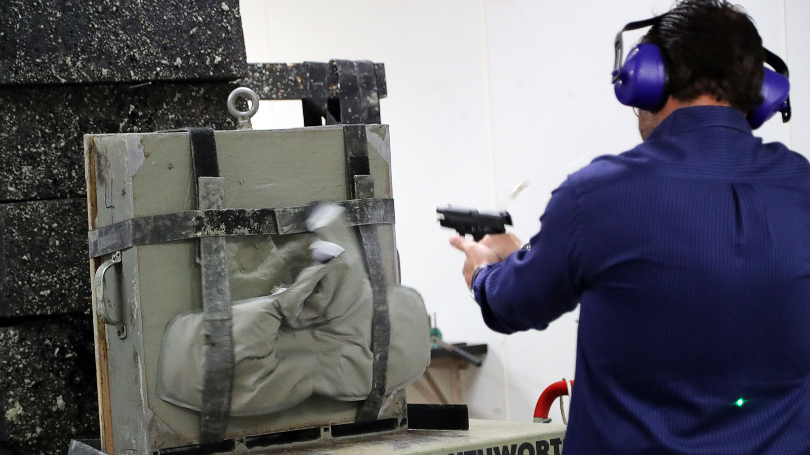 A worker at Point Blank Enterprises in Pompano Beach, FL, fires bullets into one of the company's bulletproof vests during a demonstration in 2018.