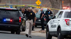 An investigator walks under crime scene tape at the scene of a shooting at Nome Park on Monday in Aurora, CO.