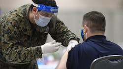 A member of the U.S. military administers a COVID-19 vaccine to a police officer at a FEMA community vaccination center in March in Philadelphia. A member of the U.S. military administers a COVID-19 vaccine to a police officer at a FEMA community vaccination center in March in Philadelphia.