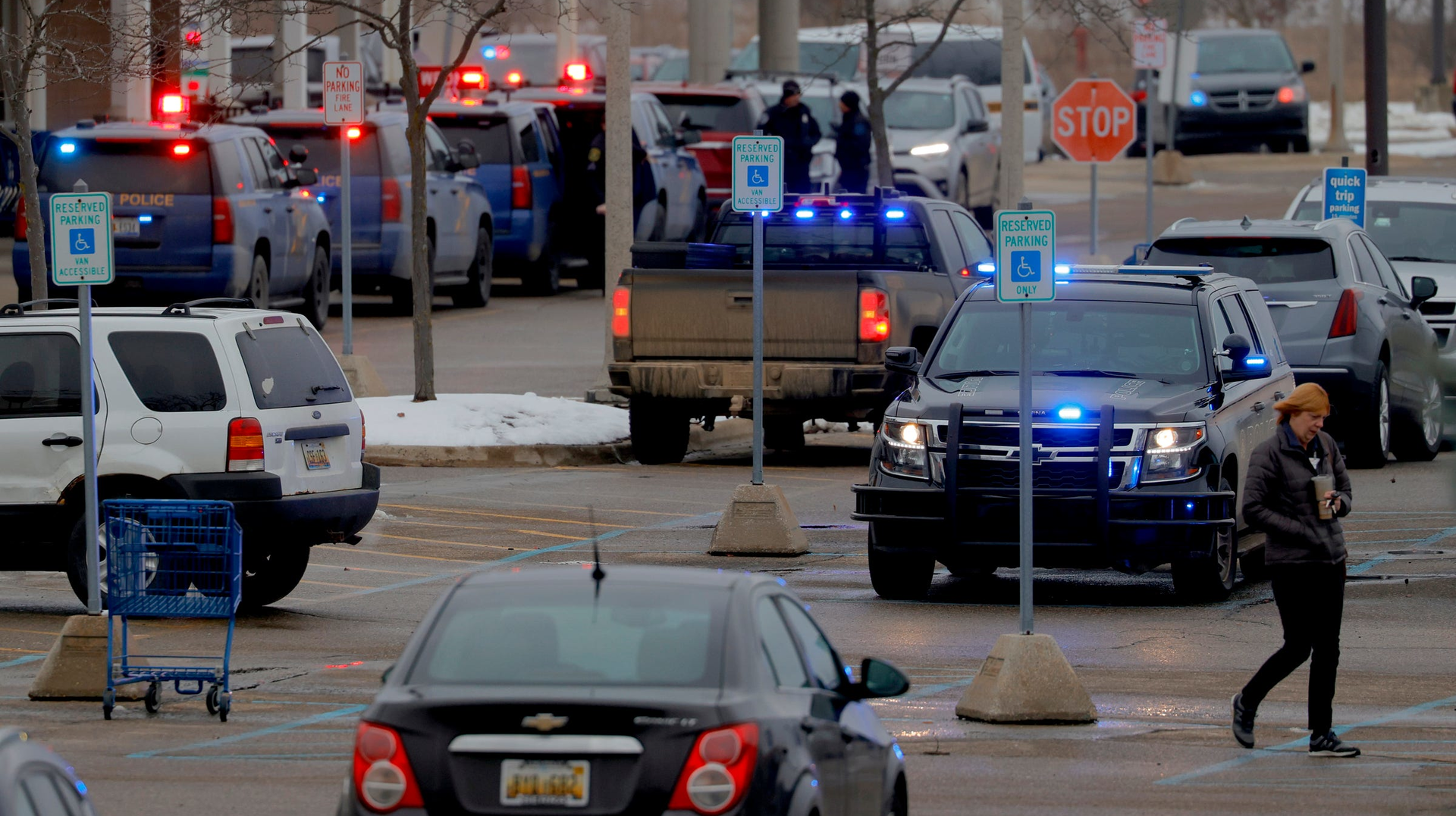 Michigan State Police and other law enforcement vehicles remained lined up at a business parking lot where students earlier had gathered following a shooting at Oxford High School on Tuesday.