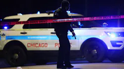 A Chicago police officer walks past a puddle of blood at the scene of a fatal shooting Friday. An 18-year-old male was shot in the neck by an unknown offender, according to police.