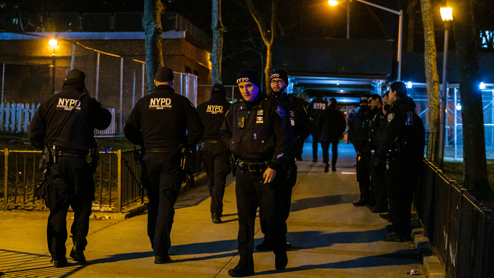 NYPD officers and detectives investigate the scene after an off-duty officer was shot in the foot near the entrance to a building in the Manhattanville Houses on Saturday.