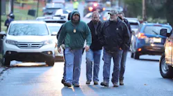 Investigators walk in the vicinity of the scene of a shooting in Lebanon, PA, on Thursday, that left a police officer dead and two seriously wounded.