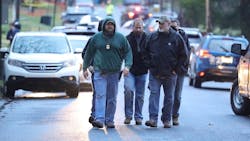Investigators walk in the vicinity of the scene of a shooting in Lebanon, PA, on Thursday, that left a police officer dead and two seriously wounded.
