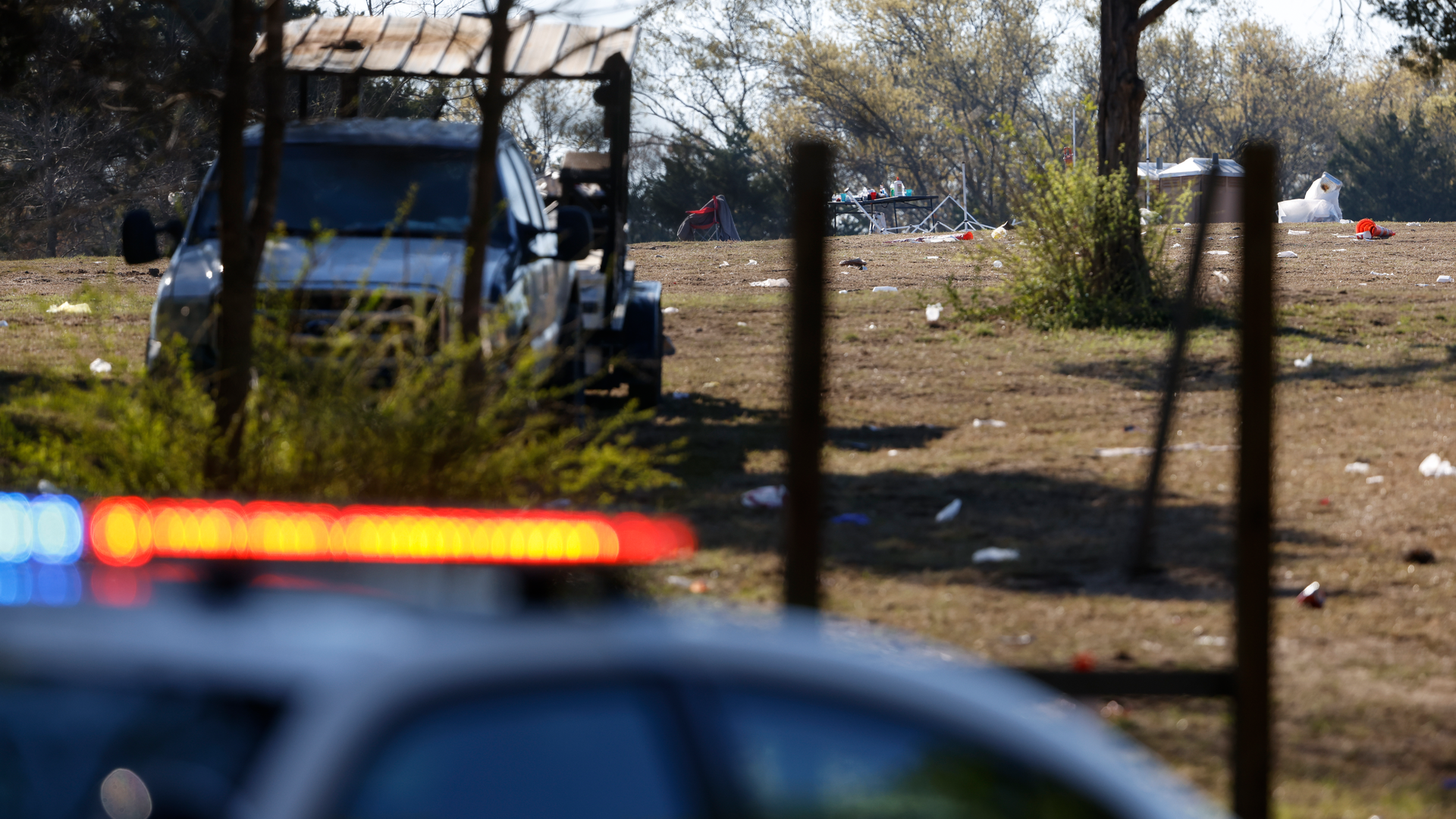 A police car sits in front of the scene where 18 people were shot and one person was killed Saturday at a concert in the Dallas neighborhood of Oak Cliff.
