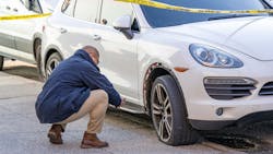 An NYPD officer inspects a blown tire after another officer opened fire at a white Porsche on the westbound Belt Parkway on Sunday.