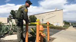 An Orange County, CA, sheriff's deputy ties crime scene tape in front of Geneva Presbyterian Church in Laguna Woods on Sunday following a shooting that killed one person and critically wounded four.