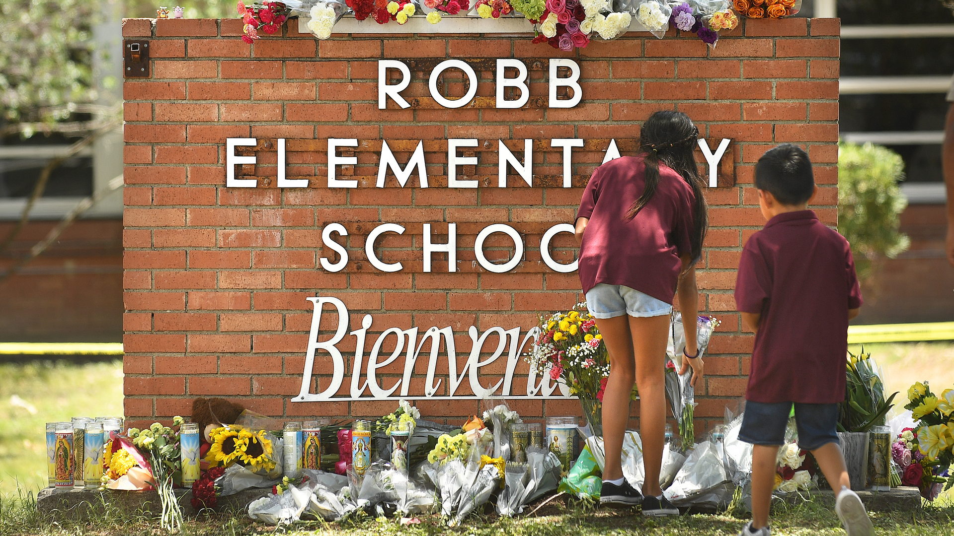 Family members who lost a sibling place flowers outside Robb Elementary School in Uvalde, Texas, on Wednesday, a day after a teen gunman killed 19 students and two teachers.