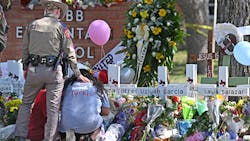 A police officer comforts family members at a memorial outside Rob Elementary School in Uvalde, TX, on Thursday. Nineteen students and two teachers died when a gunman opened fire in a classroom Tuesday.