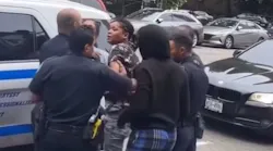 An NYPD officer was spat on and punched by a man and woman while police tried to take another woman into custody over loud music playing from a stereo in East Harlem on Tuesday.
