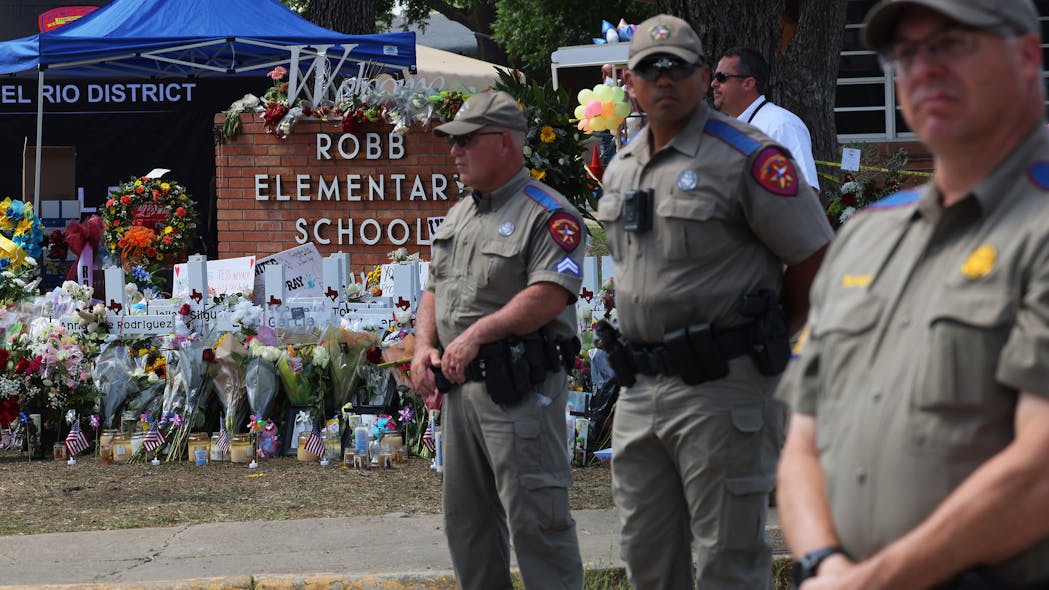 Texas Highway Patrol troopers stand at attention in front of a memorial for the victims of the mass shooting at Robb Elementary School in Uvalde, Texas, on Friday.