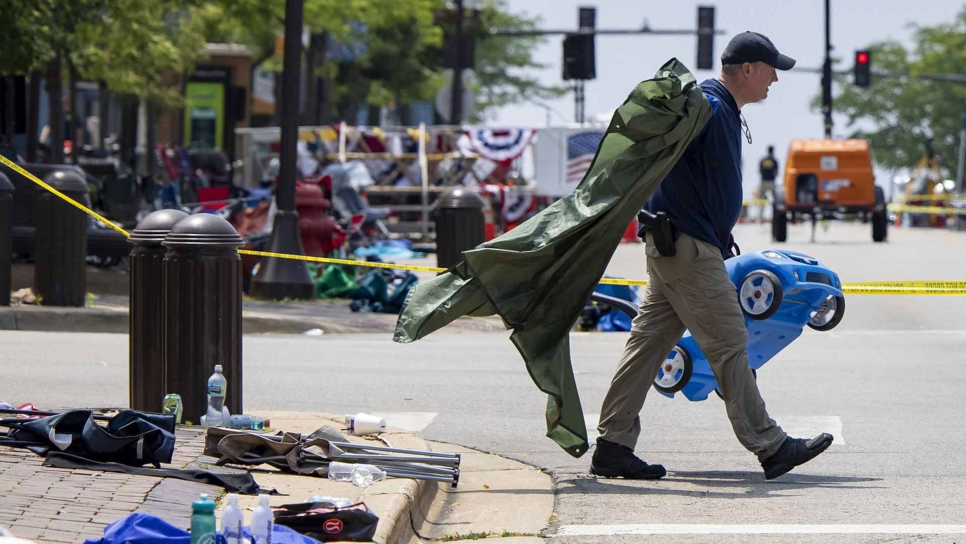 A law enforcement officer removes items left behind by parade-goers along Central Avenue on July 5 in Highland Park, IL.