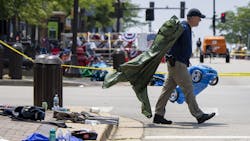 A law enforcement officer removes items left behind by parade-goers along Central Avenue on July 5 in Highland Park, IL. A law enforcement officer removes items left behind by parade-goers along Central Avenue on July 5 in Highland Park, IL.