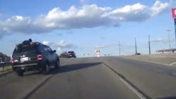 The owner of a stolen SUV hangs on to the vehicle's roof rails as an alleged thief speeds through traffic during a high-speed chase with Live Oak, TX, police Tuesday. The owner of a stolen SUV hangs on to the vehicle's roof rails as an alleged thief speeds through traffic during a high-speed chase with Live Oak, TX, police Tuesday.