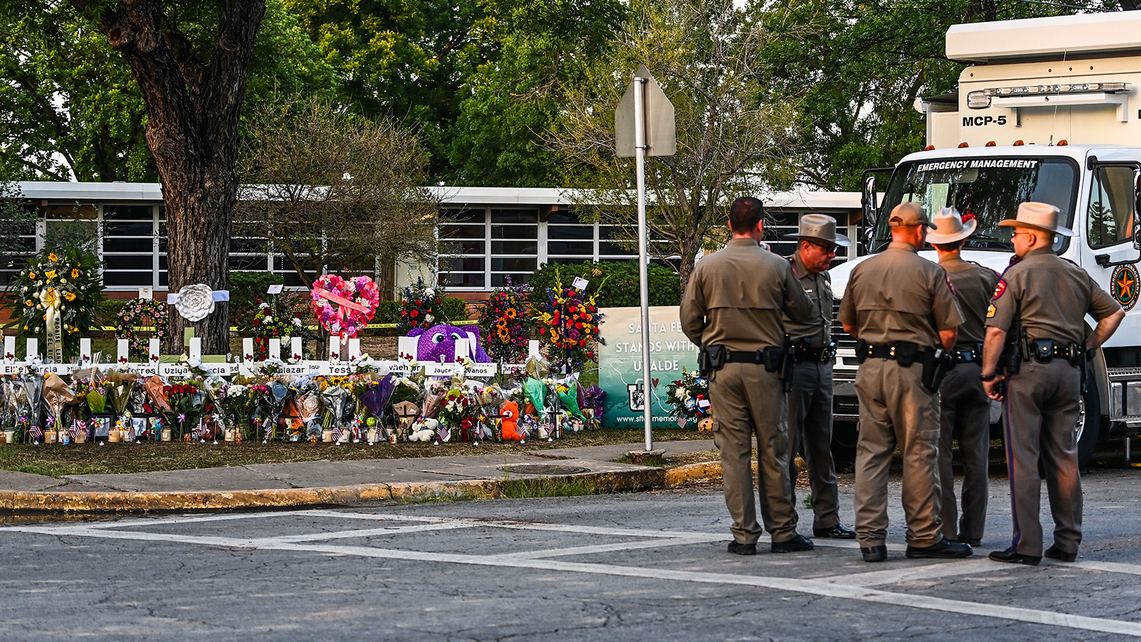 Police officers speak near a makeshift memorial for the shooting victims outside Robb Elementary School in Uvalde, TX, on May 27.