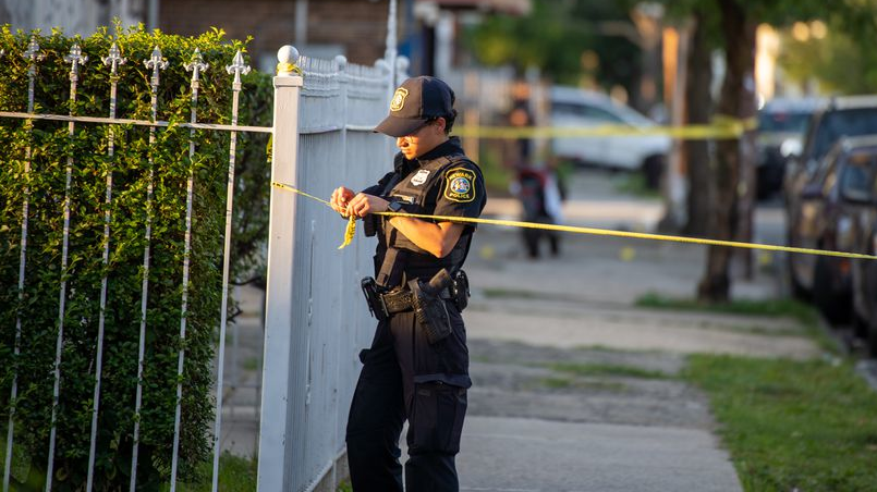 A Newark, NJ, police officer puts up caution tape on a street where a multiple shooting occurred June, 30.