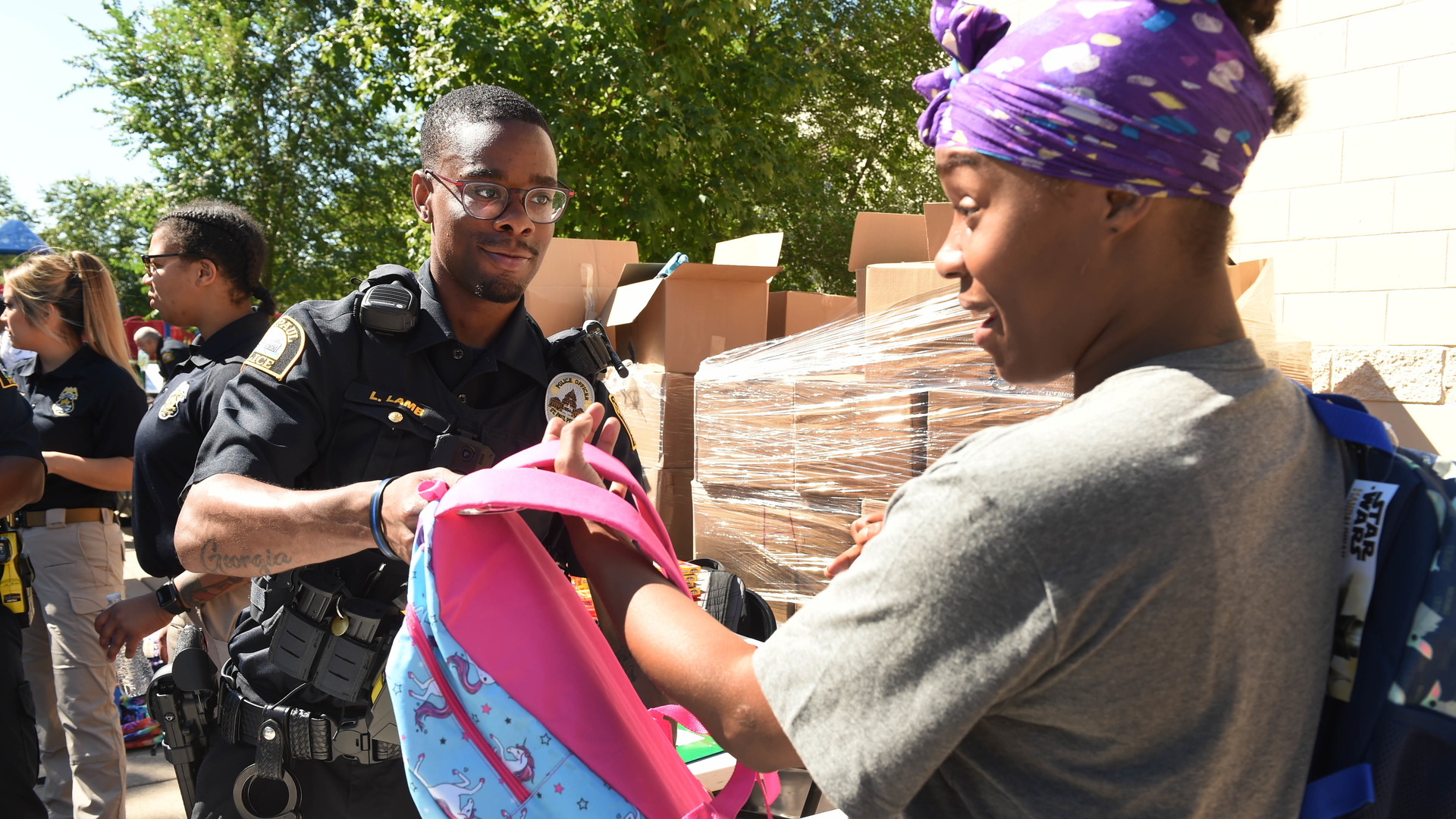 St. Paul, MN, Police Officer Lorenzo Lamb hands a backpack to Demetria Smith at the second annual Barbers & Backpacks event Tuesday at St. Paul's Conway Recreation Center. The event is sponsored by the Minnesota Chapter of the National Black Police Association.