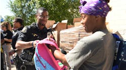 St. Paul, MN, Police Officer Lorenzo Lamb hands a backpack to Demetria Smith at the second annual Barbers &amp; Backpacks event Tuesday at St. Paul&apos;s Conway Recreation Center. The event is sponsored by the Minnesota Chapter of the National Black Police Association.