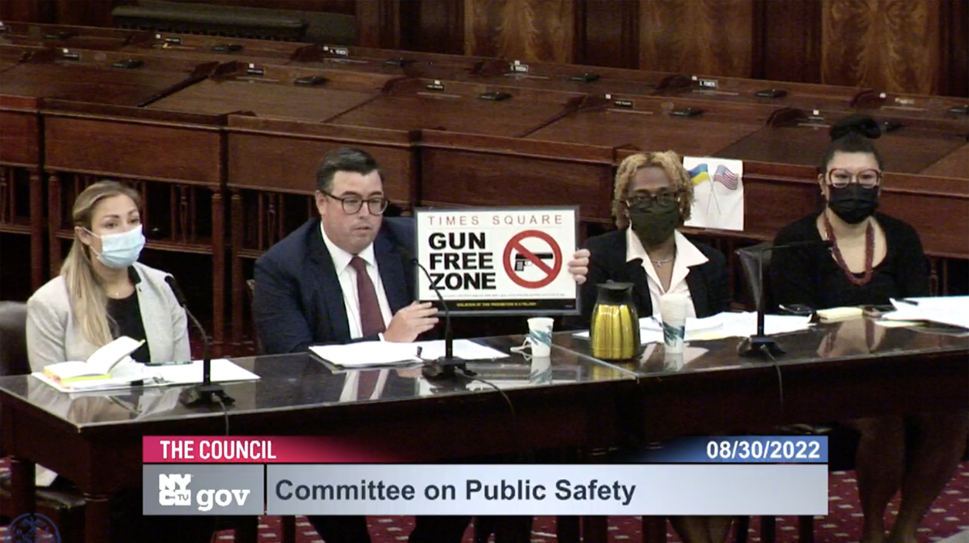 In a screen capture from a New York City Council video, Robert Barrows of the NYPD holds up a 'gun free zone' sign during a City Council Committee on Public Safety meeting Tuesday.