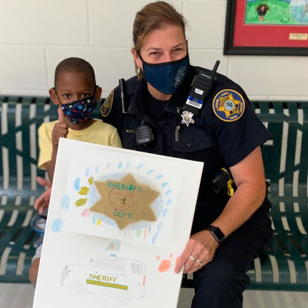 A first-grade student gives Lexington County, SC, Sheriff's Office School Resource Officer Traci Barr with framed artwork.