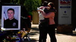 Arvada, CO, Police Officer Joe Galvez gets a hug from a friend outside of the Arvada Police Department, where a memorial has been set up for Officer Dillon Vakoff, who was killed Sunday.