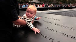 Julie Jalbert-Pitt (not pictured), who lost her father Robert Jalbert on 9/11, holds her 8-month-old daugher, Campbell Pitt, next to the name of her father on the 9/11 Memorial during the 10th anniversary ceremonies at the World Trade Center site in New York City on Sept. 11, 2011.