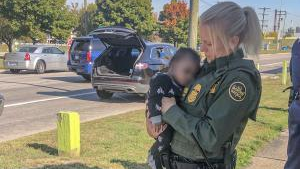 A U.S. Border Patrol agent from Michigan's Gibraltar station holds an infant who had been abducted by an armed man Wednesday.