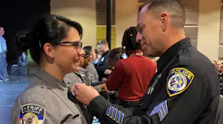 Escondido, CA, Police Sgt. Jeff Valdivia pins the badge on El Paso County, CO, Sheriff's Deputy Natalie Young at her graduation earlier this month. Valdivia had rescued her from her drug-addicted mother 22 years earlier.