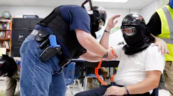 Advanced Law Enforcement Rapid Response Training instructor Will Mercado (right) observes Athens. GA. Police Officer Roger Keith (left) ties a tourniquet on a shooting victim, portrayed by fellow officer James Graham, during an active shooter training exercise in June.