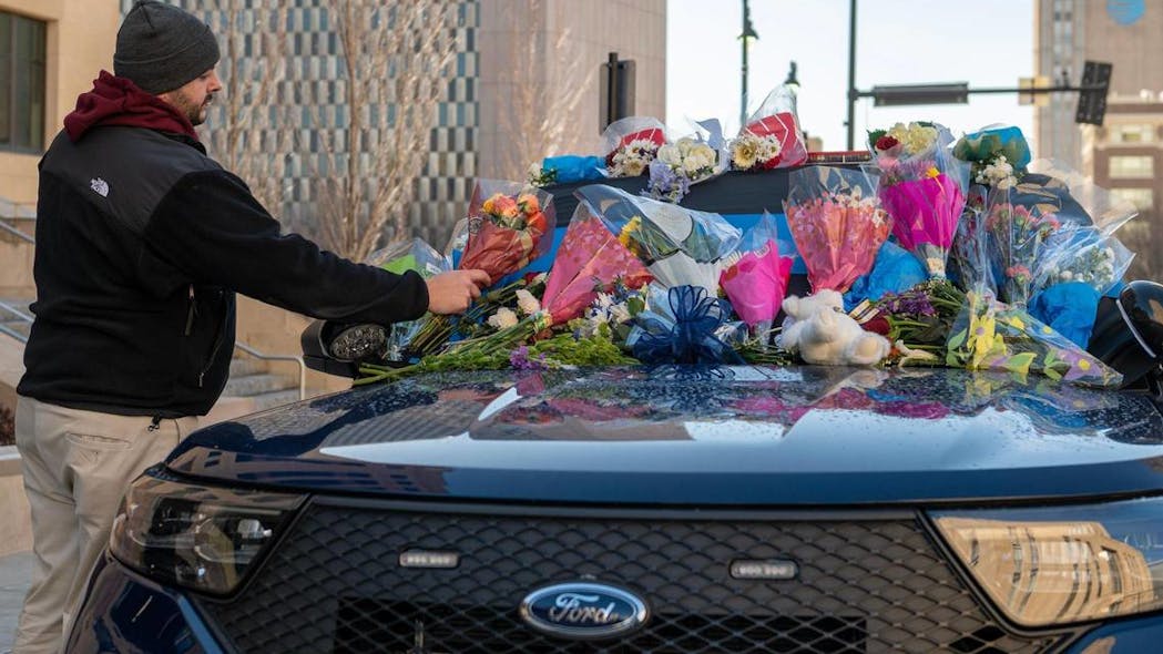 Tyler Colbert, a friend of Kansas City Police Officer James Muhlbauer, places flowers Friday on a patrol car at KCPD Headquarters. Muhlbauer and his K-9 police dog Champ were killed in a car crash Wednesday when a vehicle struck their patrol car. A pedestrian was also killed in the crash.