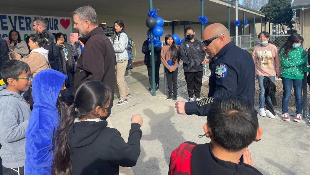 A Selma, CA, police officer prepares to fist bump Eric White Elementary students during a Tuesday event to thank the department for their commitment to the Selma Unified school community.
