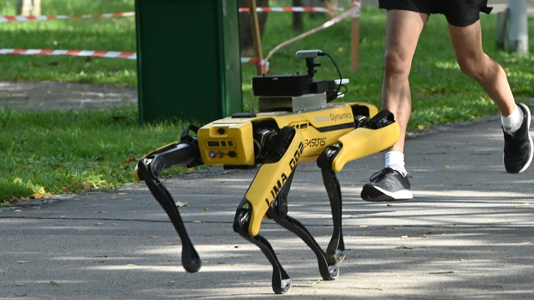 A man jogs past a four-legged robot called Spot at the Bishan-Ang Moh Kio Park in Singapore in 2020.
