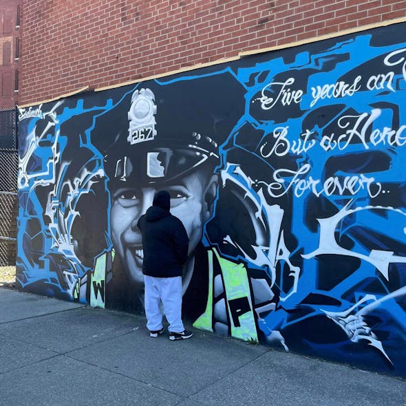 Ferdinand Nazario, the artist responsible for a mural of fallen Worcester Police Officer Emmanuel 'Manny' Familia, removed black spray paint vandals used to deface the artwork last week. Ferdinand Nazario, the artist responsible for a mural of fallen Worcester Police Officer Emmanuel 'Manny' Familia, removed black spray paint vandals used to deface the artwork last week.