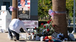 A person lights candles at a growing memorial for Los Angeles County Sheriff&apos;s Deputy Ryan Clinkunbroomer outside of the Palmdale station Monday. Clinkunbroomer was found shot in his patrol vehicle outside of the station Saturday evening.