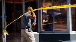 A law enforcement officer walks under caution tape Sunday at the scene of a shooting in Ybor City in Tampa, FL, that left two people dead and 18 people injured.