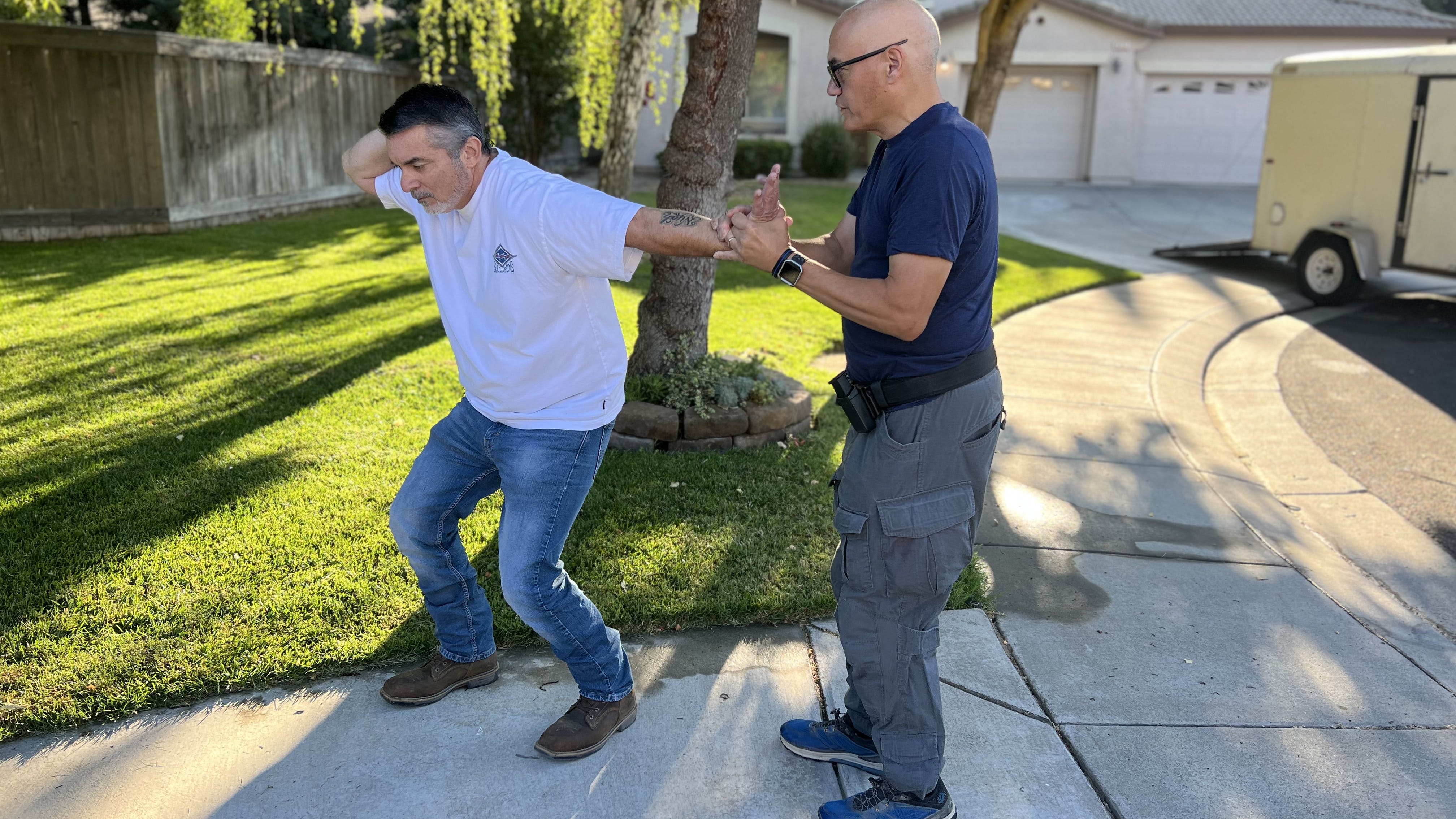 The extended wrist lock, where the hand is twisted upwards and the arm is levered down, is an effective method for keeping a little distance from the suspect. Any lock properly applied should prevent the suspect from maintaining a steady base. Notice that Lindsey is standing upright, and George is involuntarily bent down.