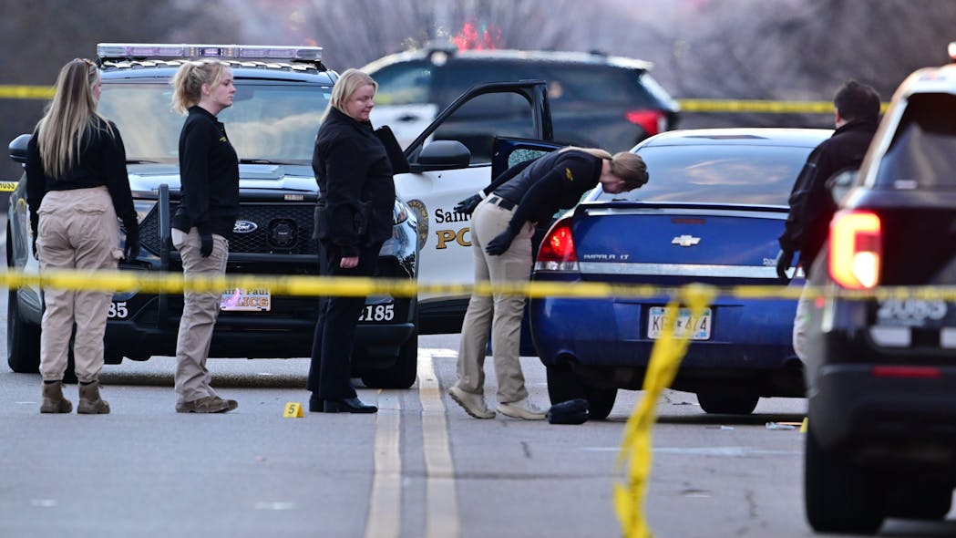 Investigators examine a car with a broken door window at the scene where a St. Paul, MN, police officer was wounded in the leg by gunfire, and a suspect also was injured Thursday.