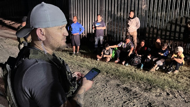 Samuel Hall, 40, North Texas-based founder of the Patriots for America militia, surveys a group of migrants stopped by U.S. Customs and Border Protection agents after crossing the Rio Grande in Eagle Pass, Texas, last month.