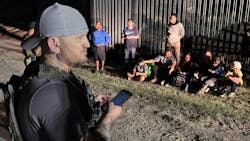 Samuel Hall, 40, North Texas-based founder of the Patriots for America militia, surveys a group of migrants stopped by U.S. Customs and Border Protection agents after crossing the Rio Grande in Eagle Pass, Texas, last month.