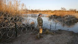 Texas National Guard Spc. Victoria Morgan walks by razor wire along the Rio Grande at Shelby Park in Eagle Pass on Feb. 1, 2024.