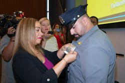 Maritza Ramos, widow of slain NYPD Officer Rafael Ramos, pins a shield on NYPD cadet Mohammed Ghafariat during graduation Tuesday in Queens.