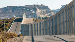The international border wall between San Diego, California and Tijuana, Mexico, is seen with an approaching U.S. Border Patrol vehicle on a nearby hill.