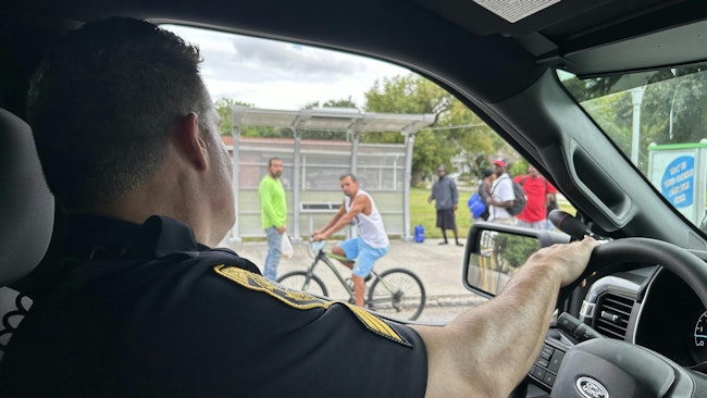 Tampa, FL, police Det. Sgt. Dimitri Angelakopoulos speaks Tuesday with people near a bus stop, urging them to seek shelter before the arrival of Hurricane Milton.