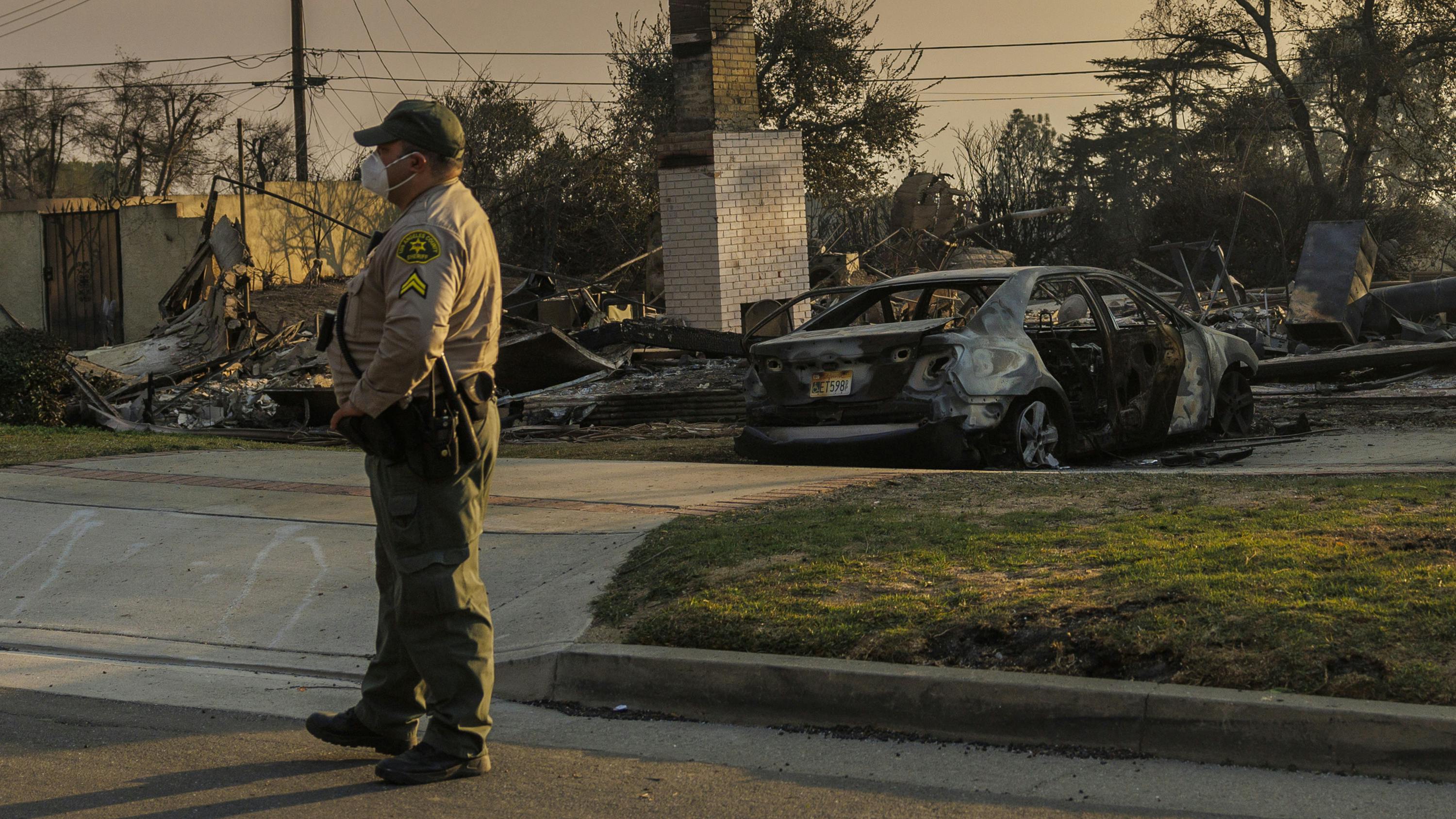 A Los Angeles County sheriff's deputy stands guard in front of a home where a resident was killed during the Eaton Fire on Jan. 9 in Altadena.