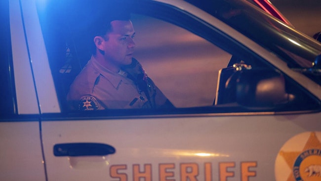 Los Angeles County Sheriff's Deputy Scott Carter runs a driver's license while temporarily detaining two men in 2019.