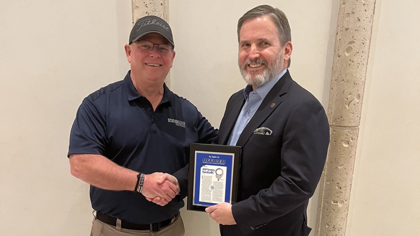 OFFICER Magazine Associate Publisher Tom Burr presents Michael Hess of ASP with the company's OFFICER Labs plaque at SHOT Show.